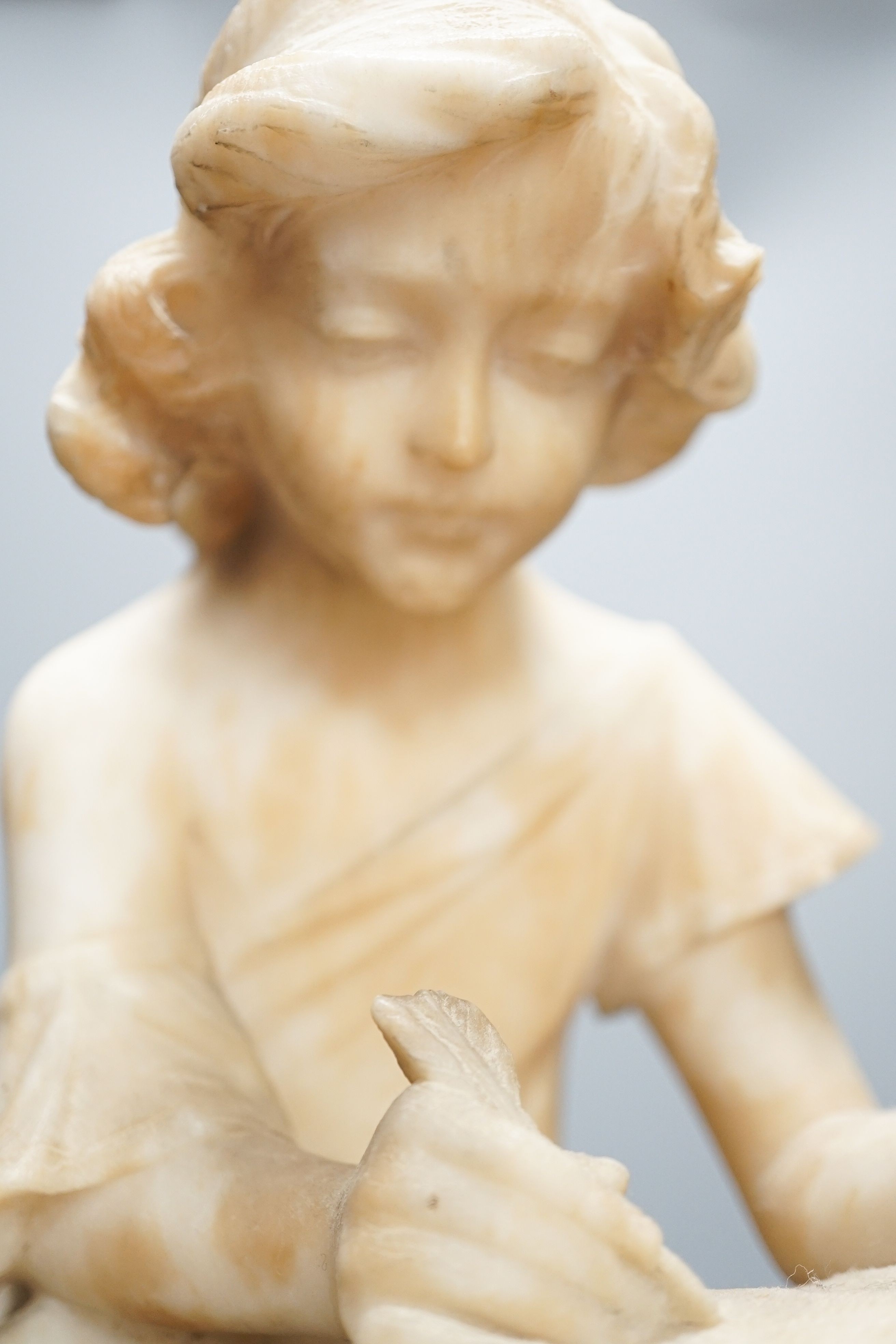 A late 19th century Italian carved alabaster figure of a girl seated, writing at a pillar 47cm